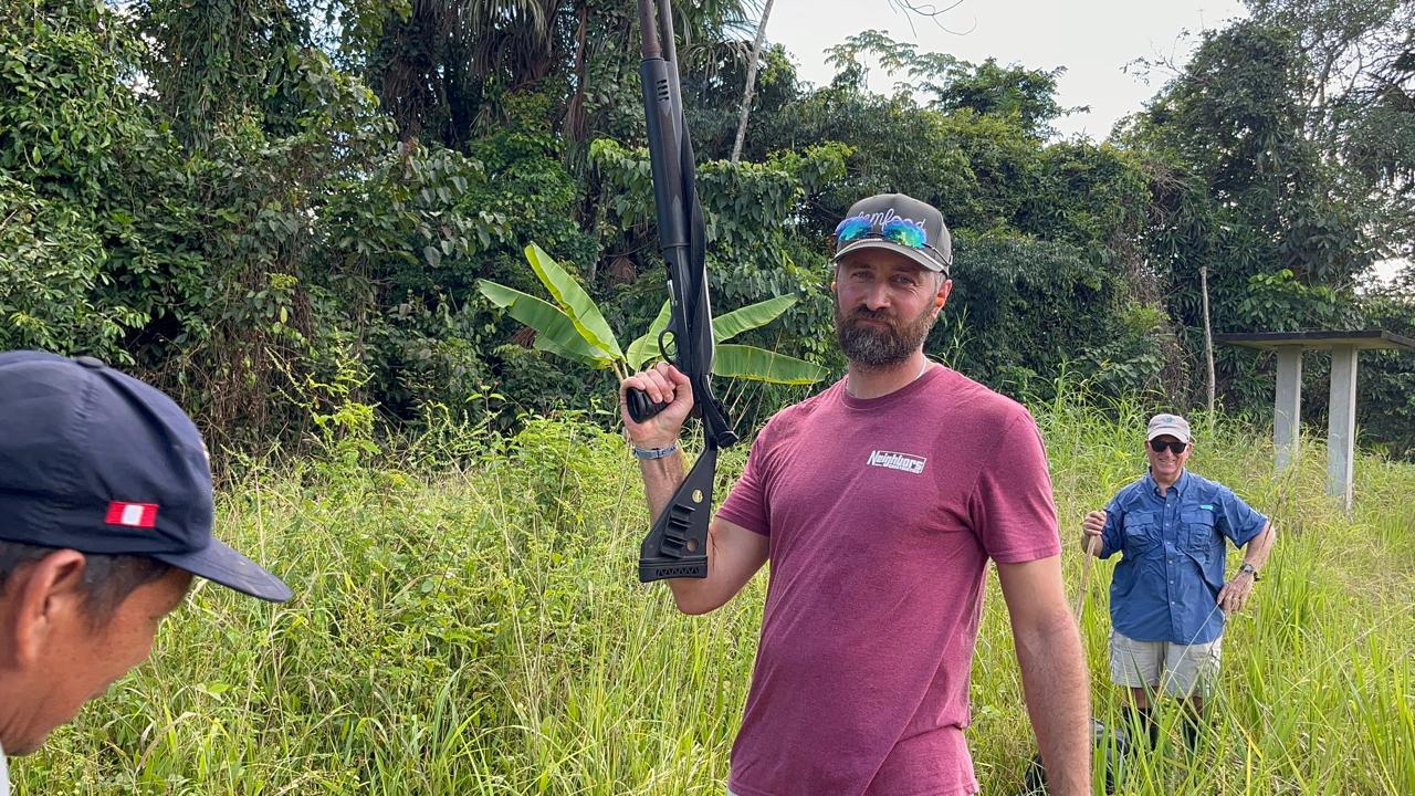 Jordan holding a shotgun upright with the team on a jungle path