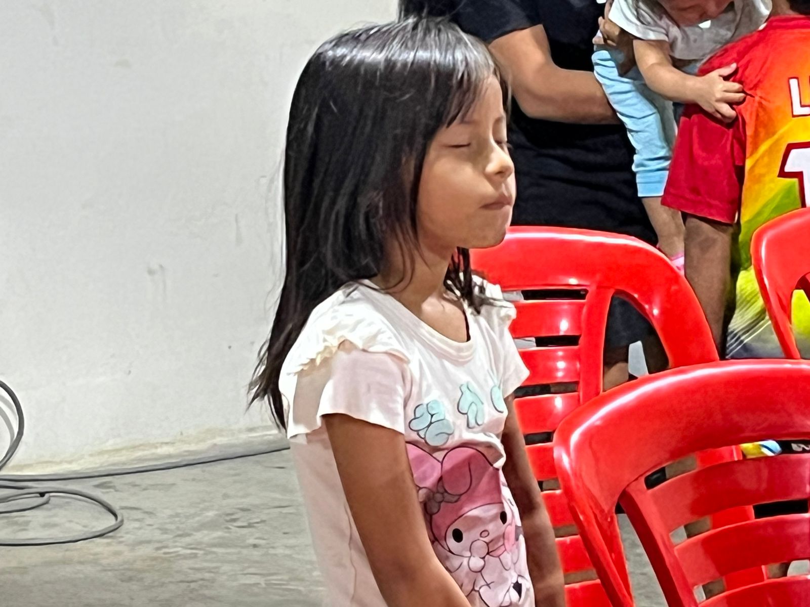 A young girl with eyes closed in prayer during a service