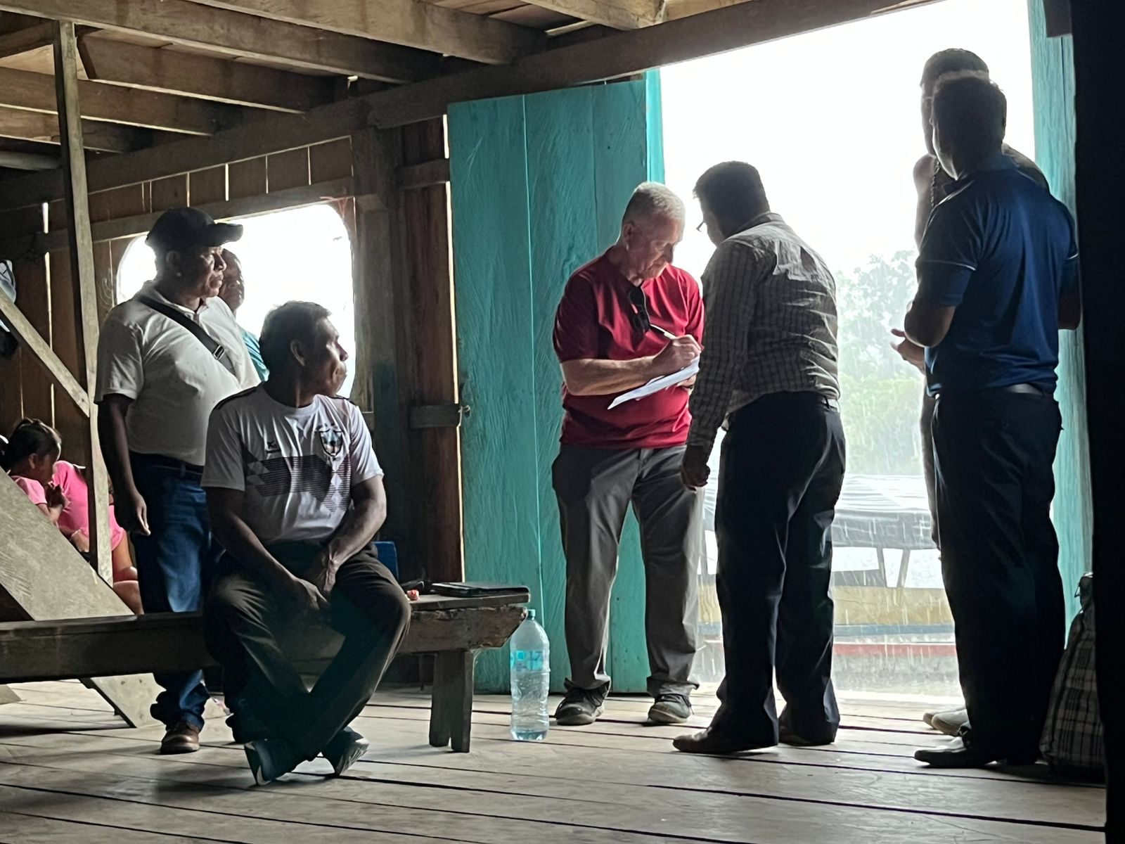 Leaders standing and talking inside a wooden riverside building during a planning meeting