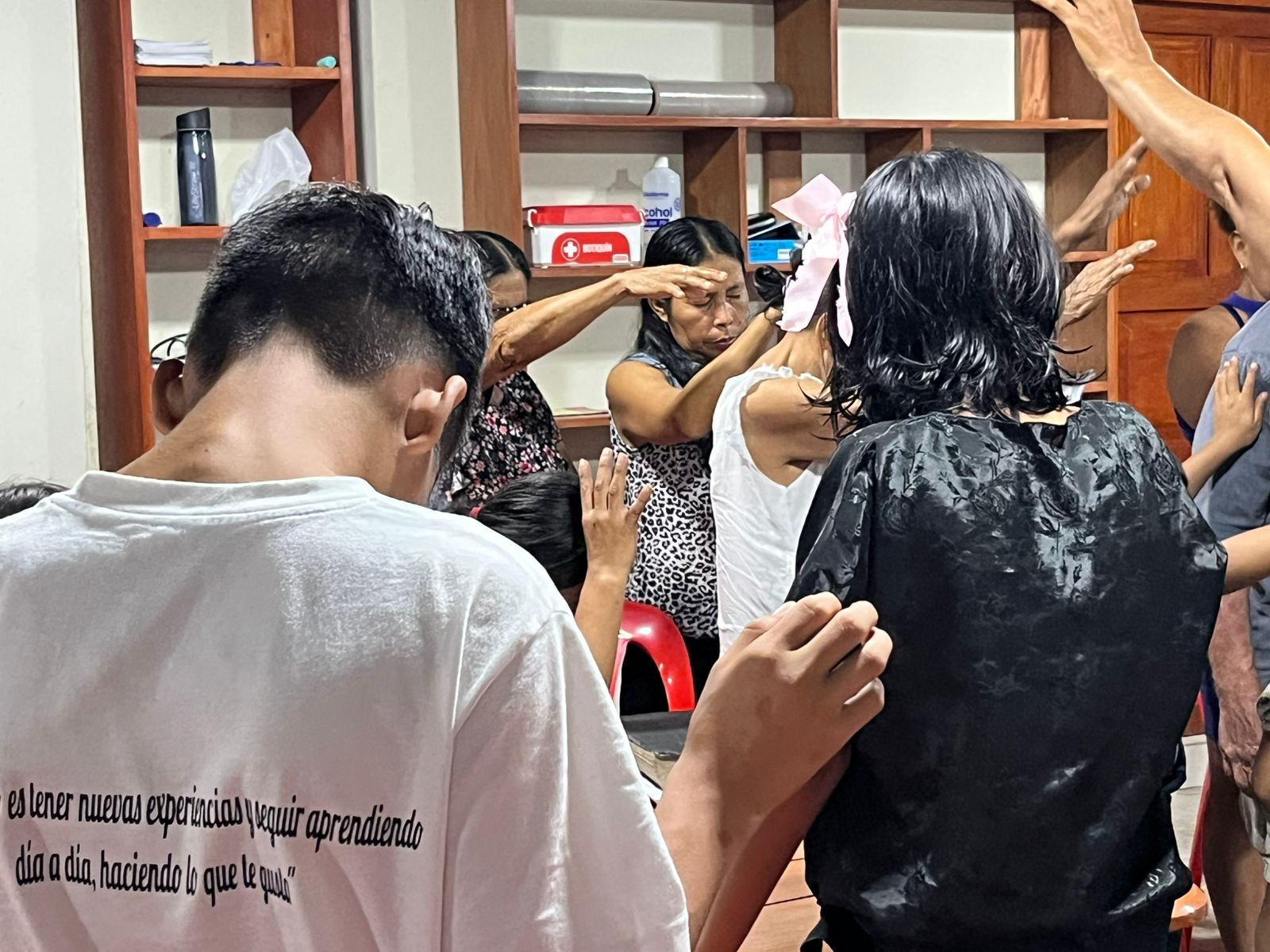 Believers laying hands and praying for a woman with a pink bow in her hair