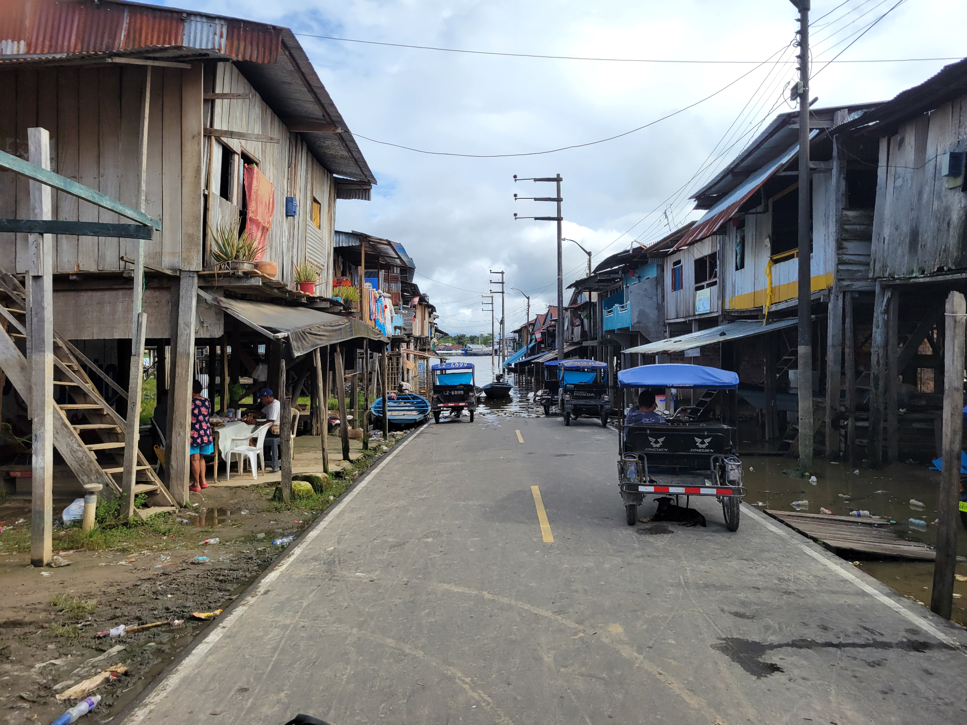 Raised wooden homes lining a road with high water at the edge of town