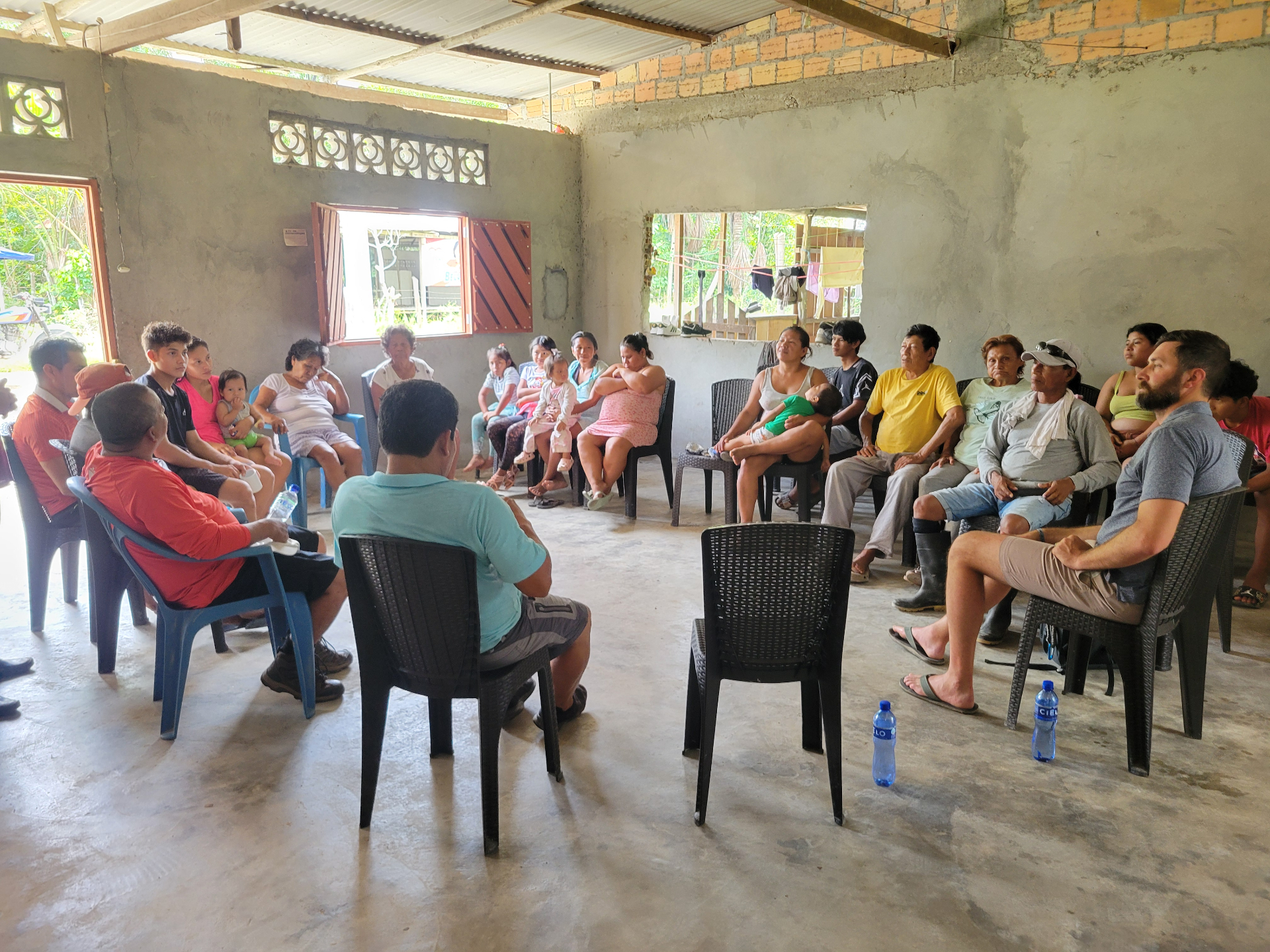 Families seated together in a concrete-walled meeting room